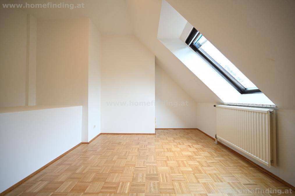 Heller Raum mit Parkettboden, Dachschräge und einem Dachfenster für natürliches Licht.