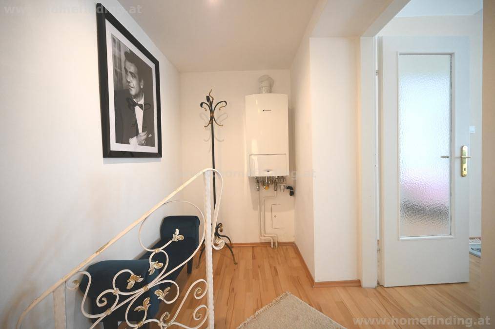 Heller Flur mit Holzboden, Heizungsanlage und Garderobe, die einen einladenden Eingangsbereich schafft.