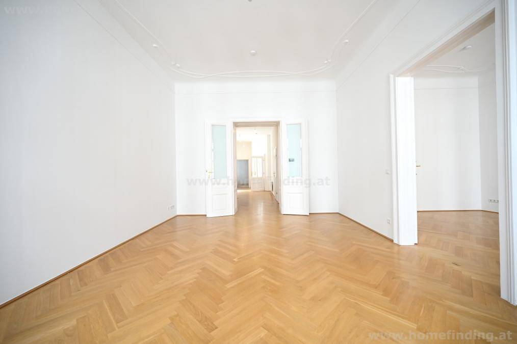 Geräumiges Zimmer mit klassischem Fischgrätparkett und eleganten Doppeltüren.