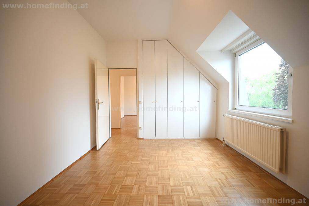 Schlafzimmer mit Parkettboden, Dachschräge und praktischen Einbauschränken.