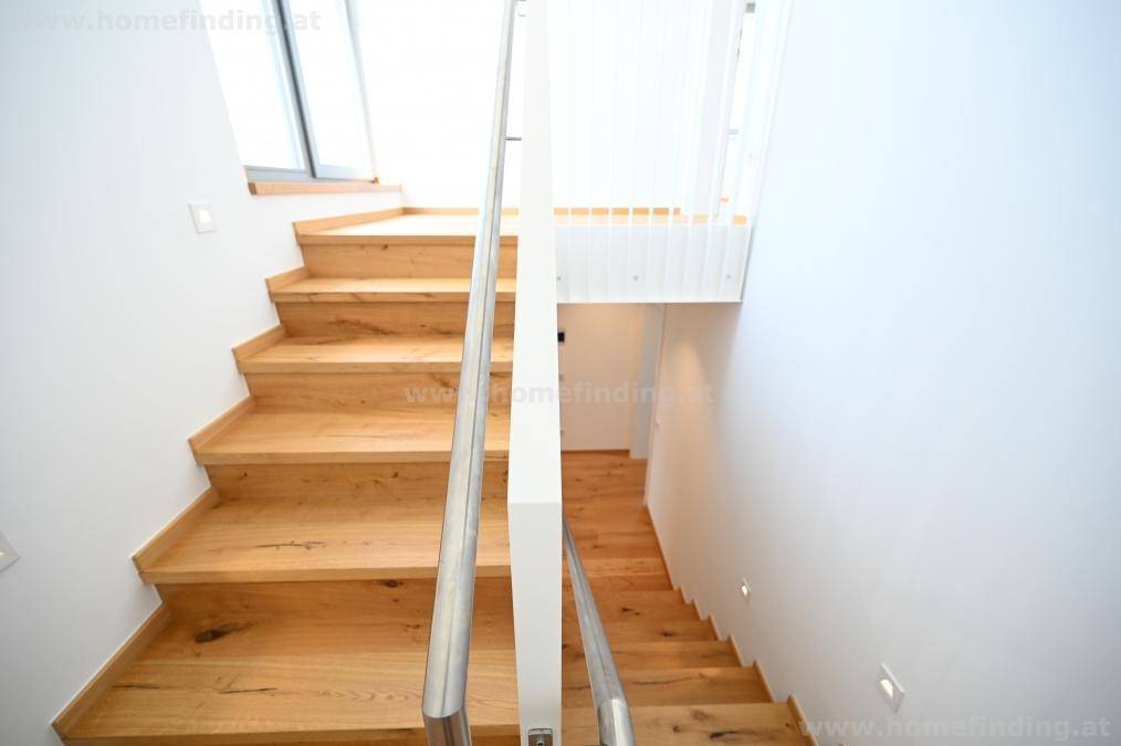 Helle Holztreppe mit modernem Metallgeländer, die die verschiedenen Etagen des Hauses verbindet.