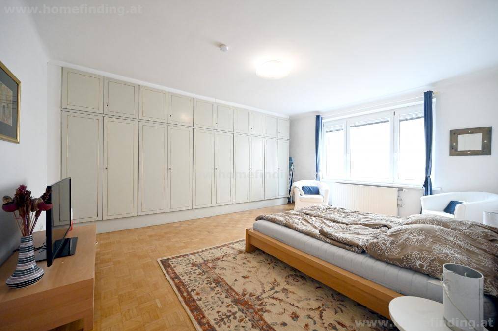 Geräumiges Schlafzimmer mit einer langen Reihe von Einbauschränken und hellem Parkettboden.