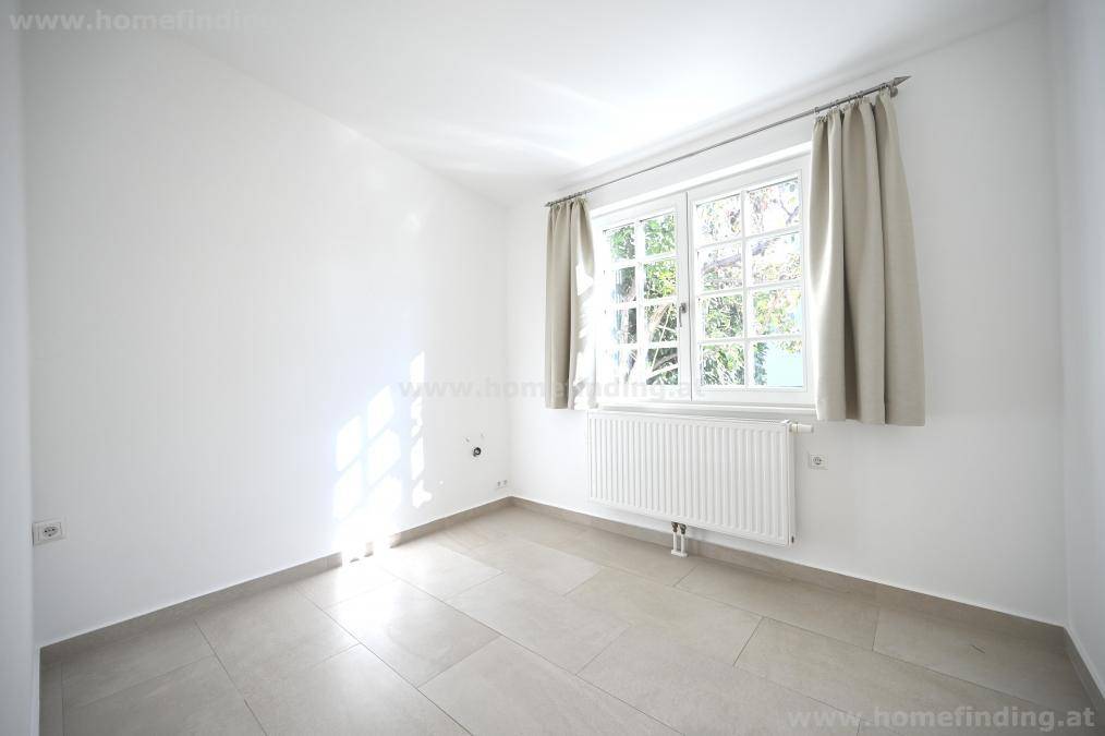 Helles Schlafzimmer mit großem Fenster, Heizkörper und neutralem Fliesenboden.