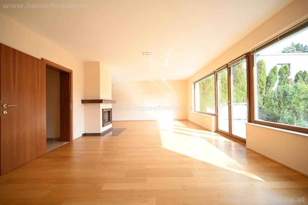 Lichtdurchflutetes Wohnzimmer mit Kamin und großen Fenstern, die den Raum hell und einladend wirken lassen.