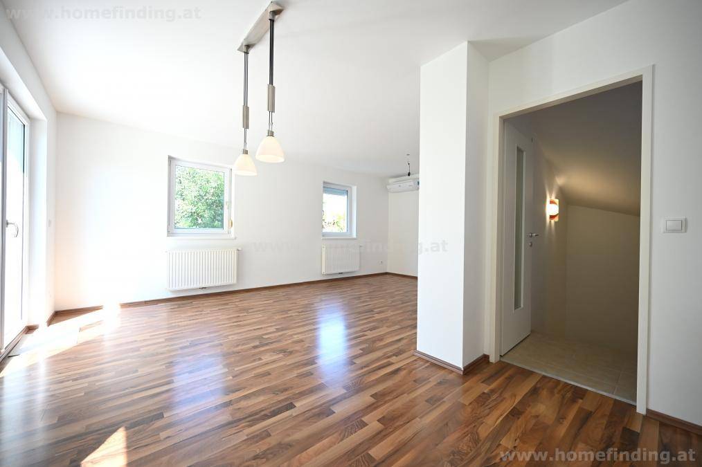 Heller Wohnbereich mit Parkettboden und offenem Übergang zu weiteren Räumen im Haus.
