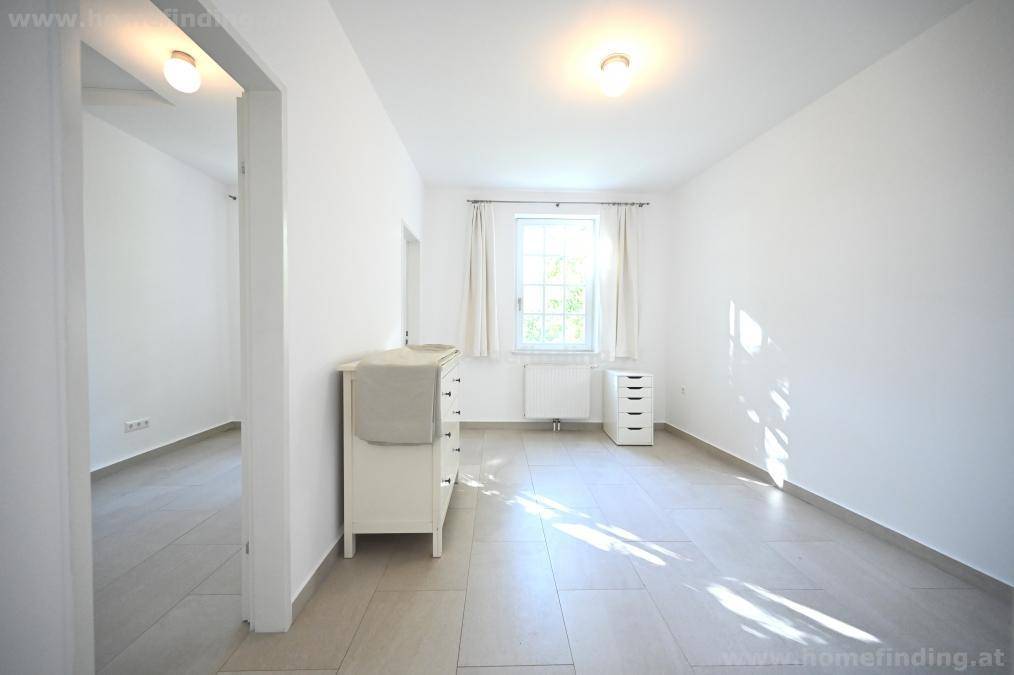 Geräumiges Schlafzimmer mit viel Tageslicht, Kommode und Blick in den angrenzenden Raum.