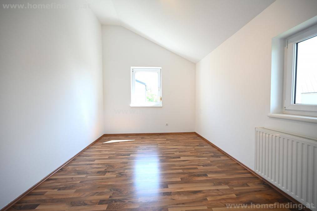 Helles Schlafzimmer im Dachgeschoss mit Parkettboden, schrägen Wänden und zwei Fenstern.