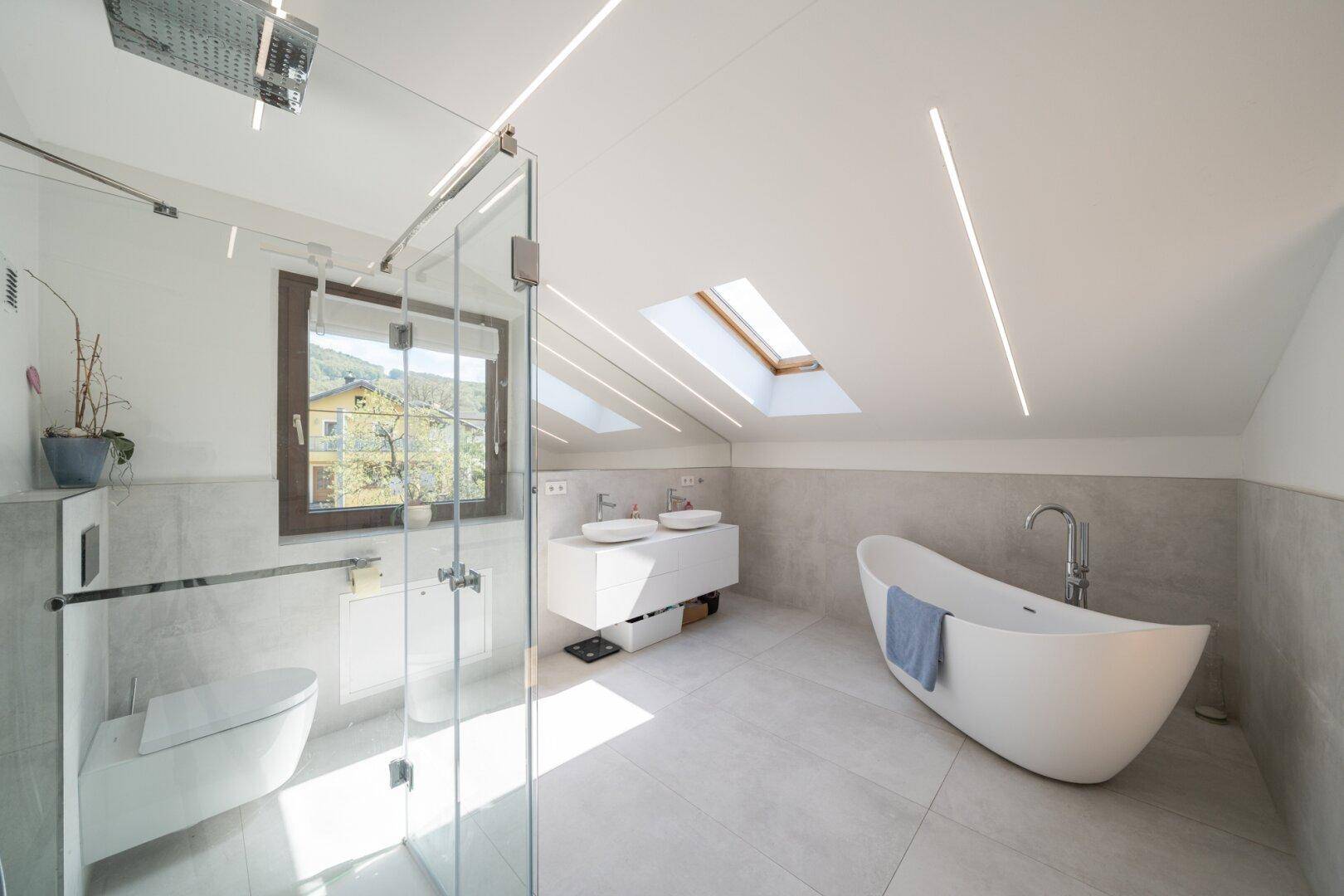 Modernes Badezimmer im Dachgeschoss mit freistehender Badewanne, Dusche und Dachfenstern.