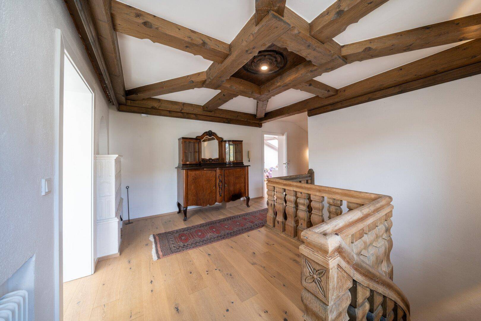 Obergeschoss-Flur mit kunstvollen Holzbalken an der Decke und traditionellem Sideboard.