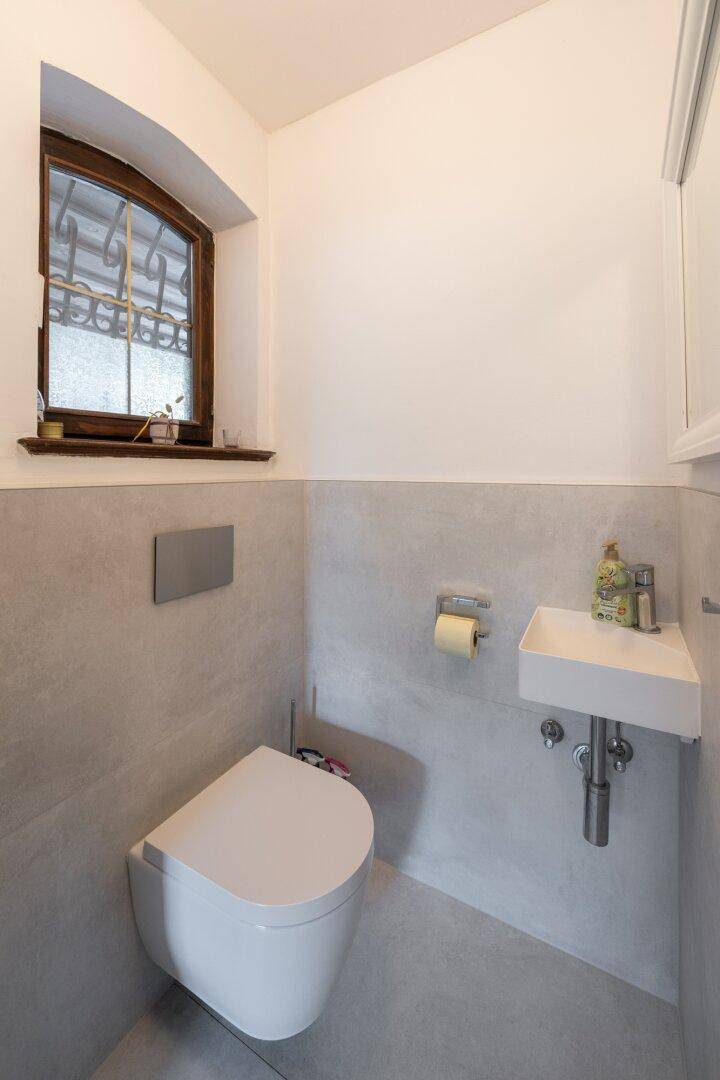 Kleines Gäste-WC mit modernem Wand-WC, Waschbecken und Fenster.