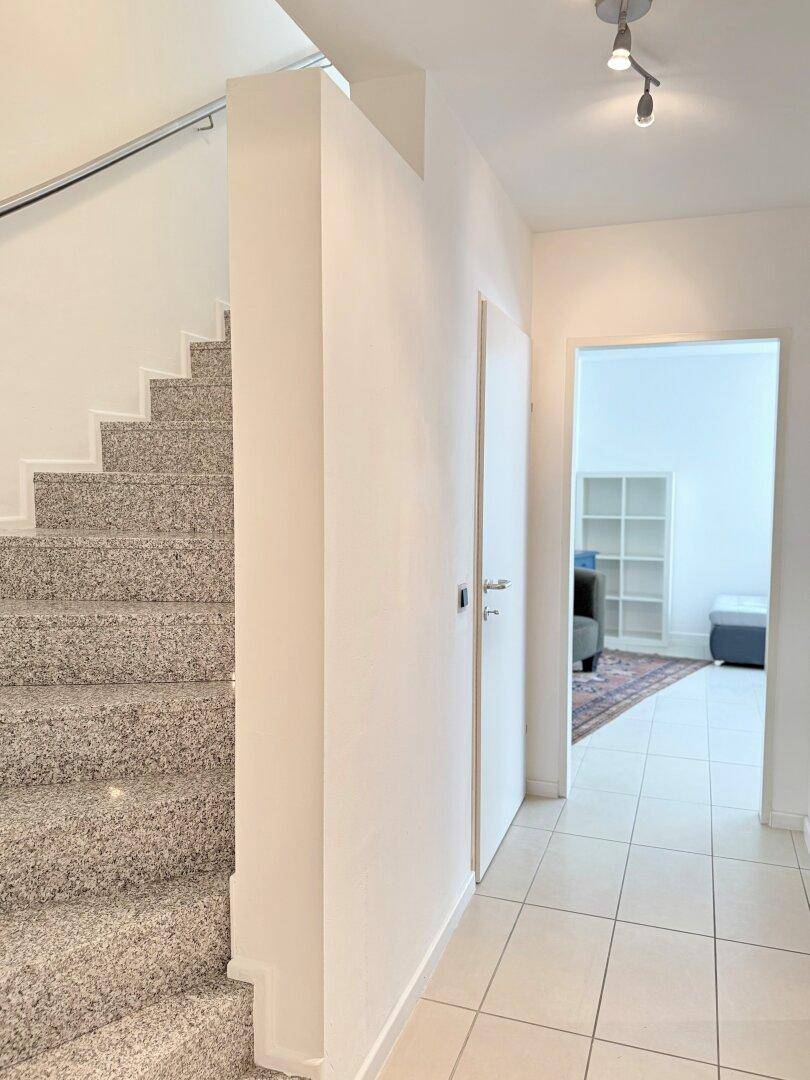 Eingangsbereich mit Treppe, Fliesenboden und Zugang zu weiteren Wohnräumen.