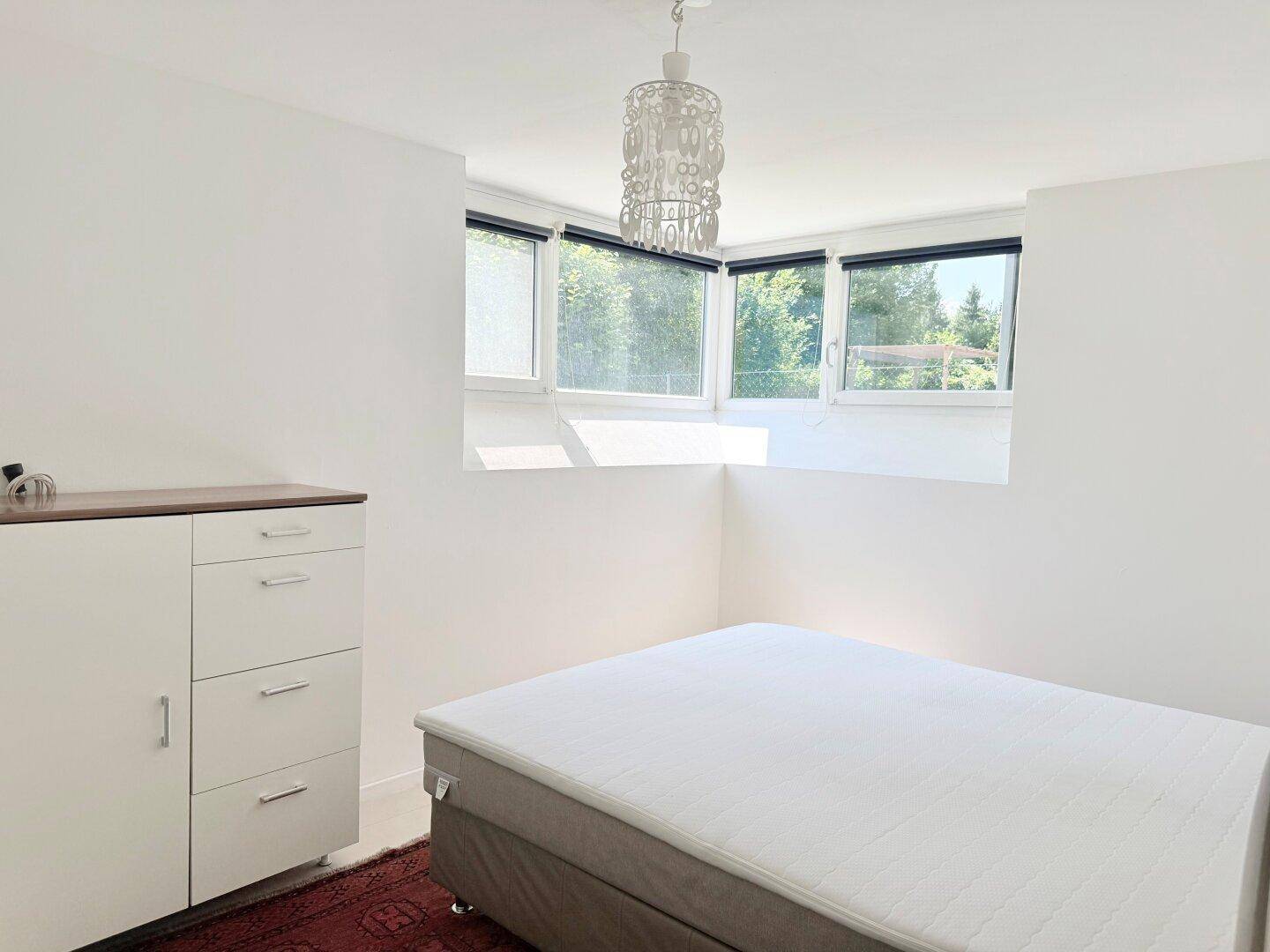 Helles Schlafzimmer mit großzügigen Fenstern und Blick ins Grüne.