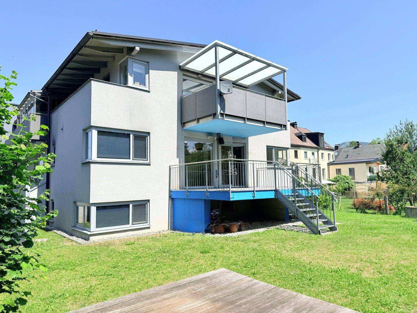 Ansicht des modernen Gebäudes von der Gartenseite mit Balkon und Rasenfläche.