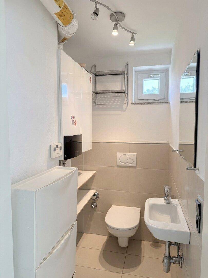 Kleines Gäste-WC mit Fenster, Wand-WC und modernem Waschbecken.