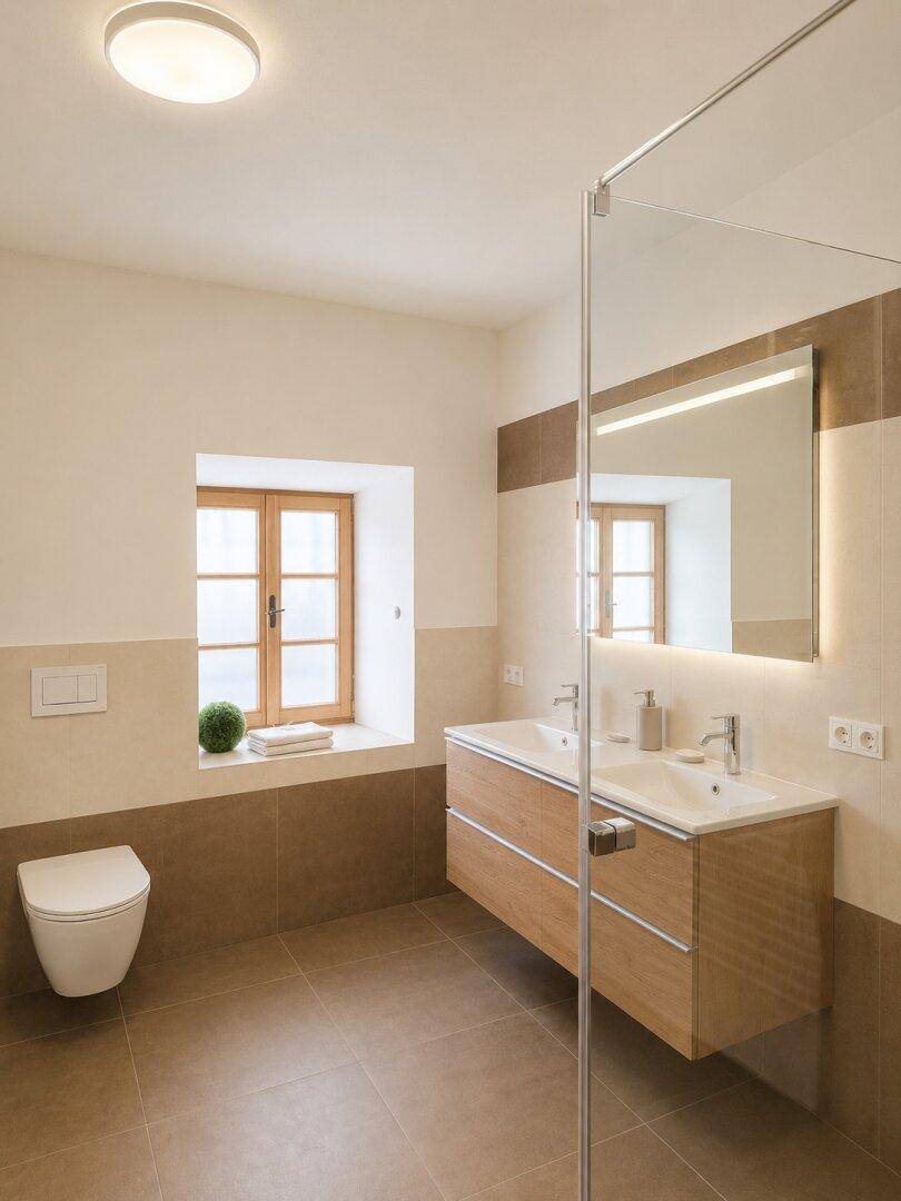 Modernes Badezimmer mit Doppelwaschbecken, bodengleicher Dusche und Fenster für Tageslicht.