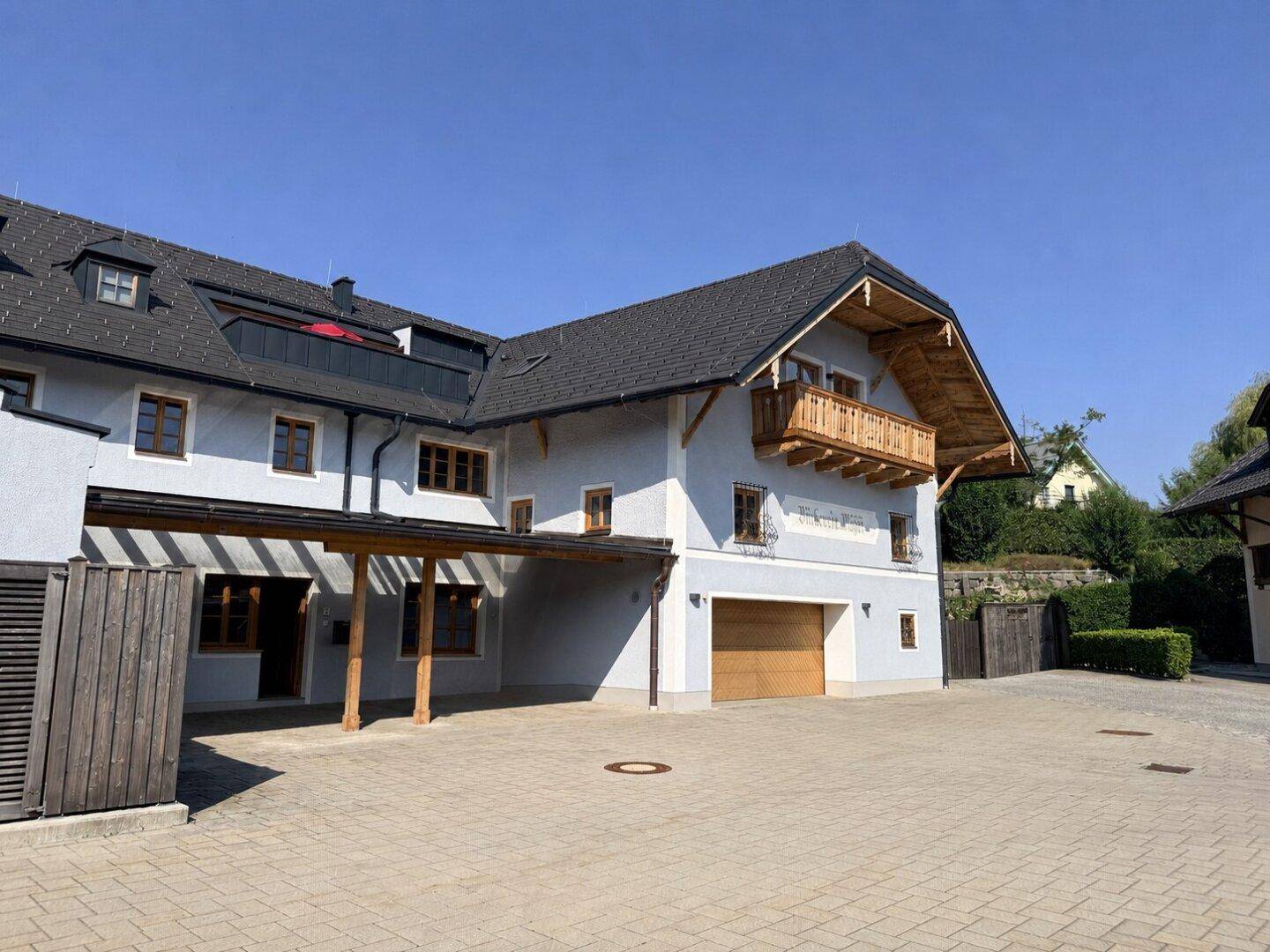 Attraktives Mehrfamilienhaus mit traditionellem Holzbalkon, Carport und integrierter Garage.