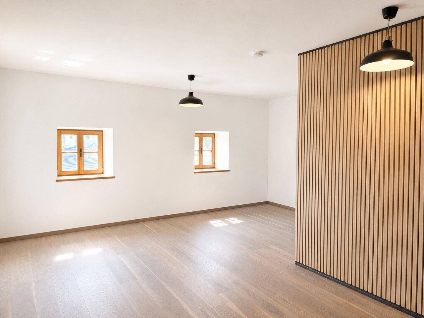Heller Raum mit Holzboden und einer modernen Akzentwand aus Holzlamellen, vielseitig nutzbar.