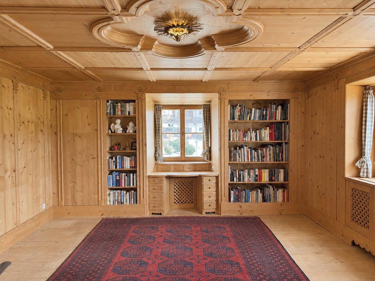 Arbeitszimmer mit umfassender Holztäfelung, eingebauten Bücherregalen und einem verzierten Deckenmedaillon.