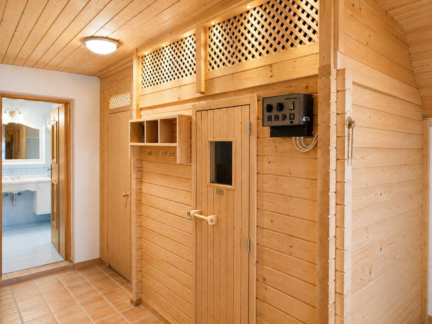 Gemütlicher Wellnessbereich mit einer holzvertäfelten Sauna und Zugang zu einem Badezimmer.