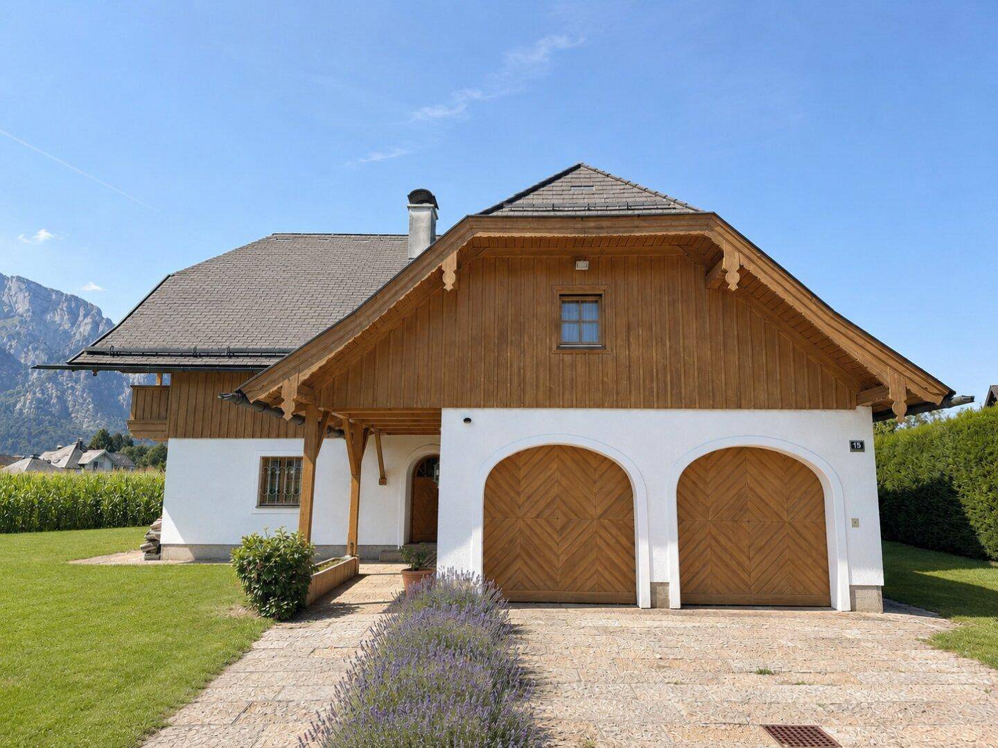 Vorderansicht des Hauses mit Doppelgarage, gepflasterter Auffahrt und Lavendelbeeten.