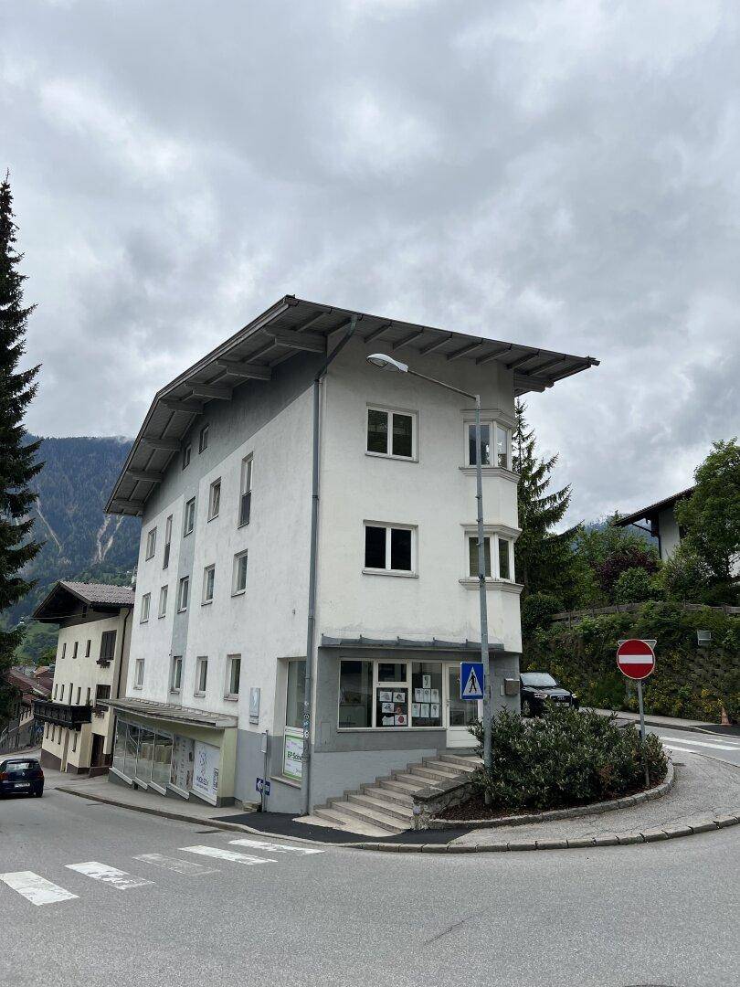 Eckansicht des Gebäudes von der Straße, mit mehreren Etagen und Geschäftsflächen im Erdgeschoss.