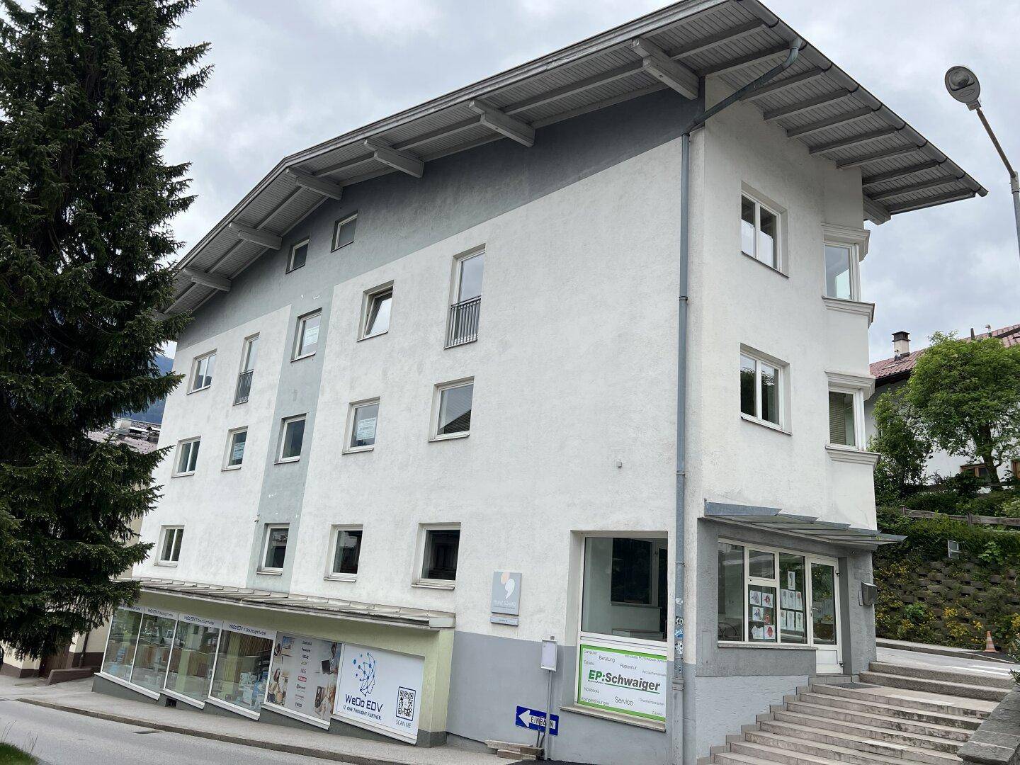 Weitere Eckansicht des Gebäudes mit Geschäftsflächen im Erdgeschoss und Wohnungen darüber.