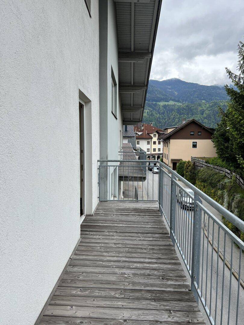 Langer Balkon mit Holzboden und Metallgeländer, bietet einen weiten Blick auf die umliegenden Berge.
