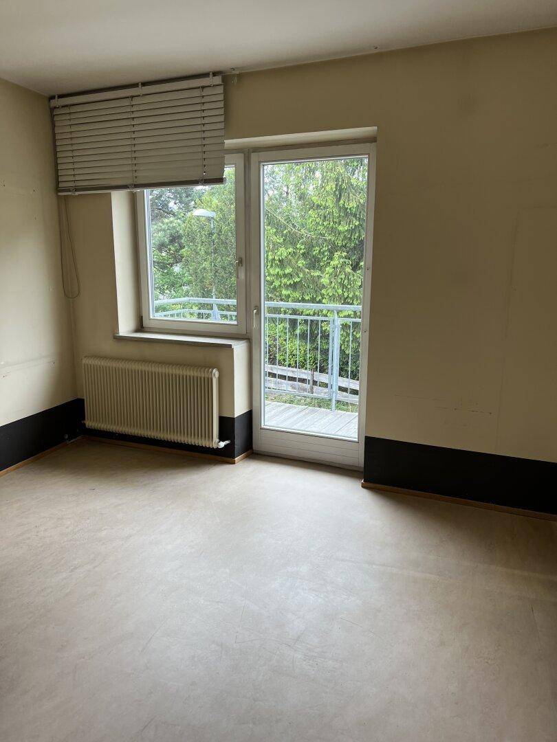 Helles Zimmer mit Fenster und Balkonzugang, ausgestattet mit strapazierfähigem Bodenbelag.