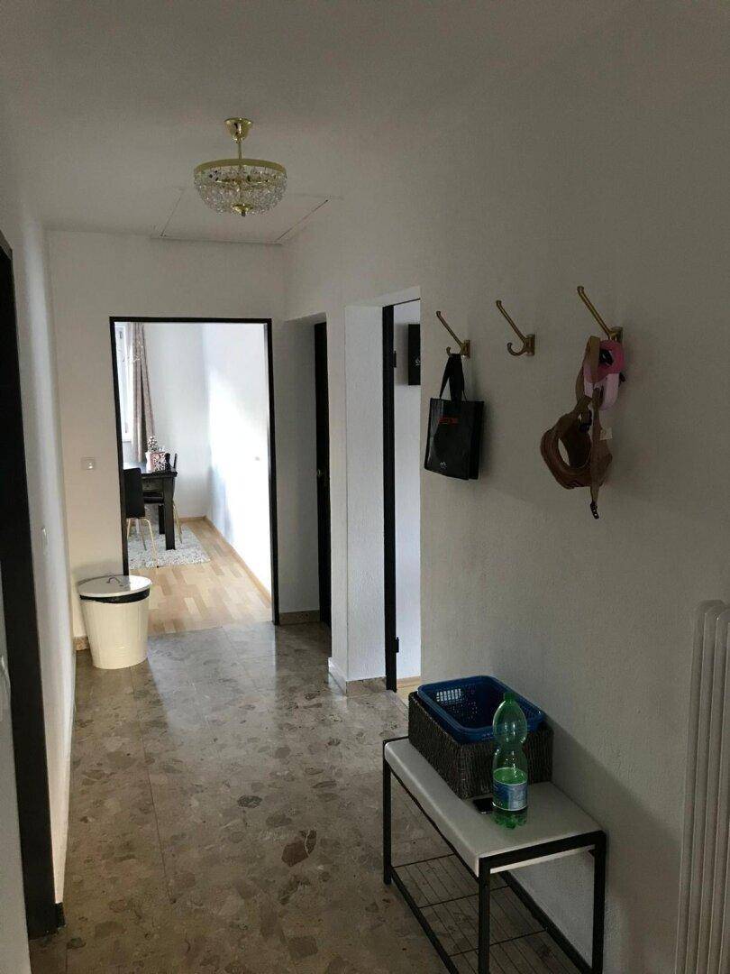 Geräumiger Flur mit Steinboden und Garderobe, der zu weiteren Zimmern der Wohnung führt.