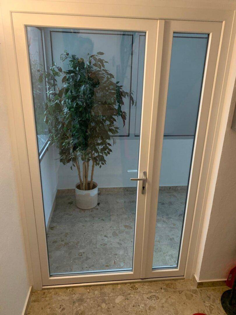 Heller Wintergarten mit großem Fenster und einer dekorativen Pflanze, ideal für entspannte Stunden.