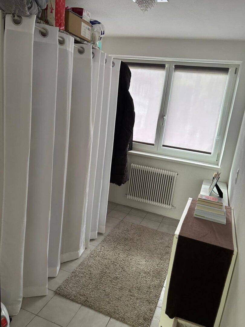 Praktischer Abstellraum mit Fenster, Heizung und Vorhängen zur Organisation von Gegenständen.