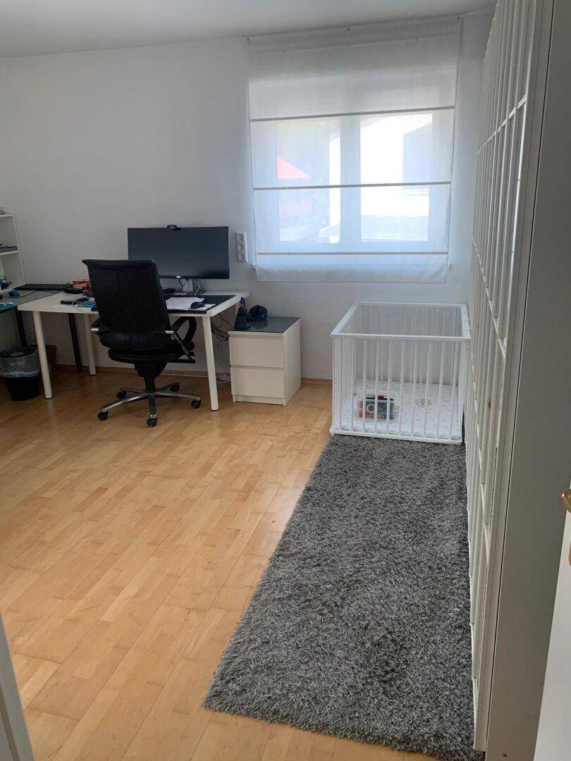 Helles Arbeitszimmer mit Schreibtisch, Bürostuhl und Laminatboden, ideal für Home-Office.