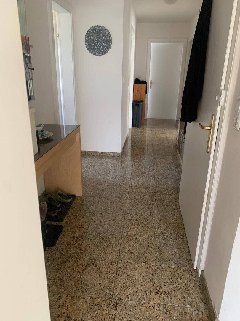 Heller Flur mit Granitboden und Garderobe, der zu den Wohnbereichen der Immobilie führt.