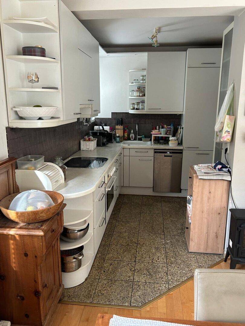 Funktionale Küche mit weißen Schränken, Spülmaschine und Fliesenboden, gut ausgestattet.