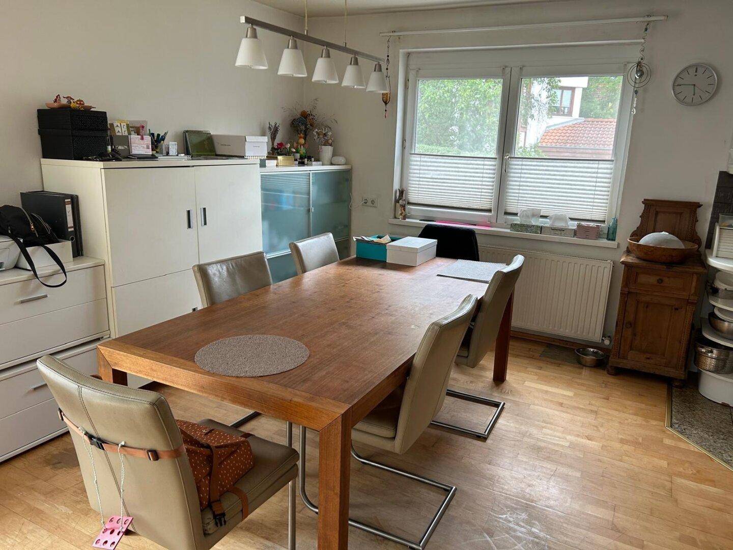 Geräumiges Esszimmer mit großem Holztisch, Stühlen und Fenster mit Blick ins Grüne.