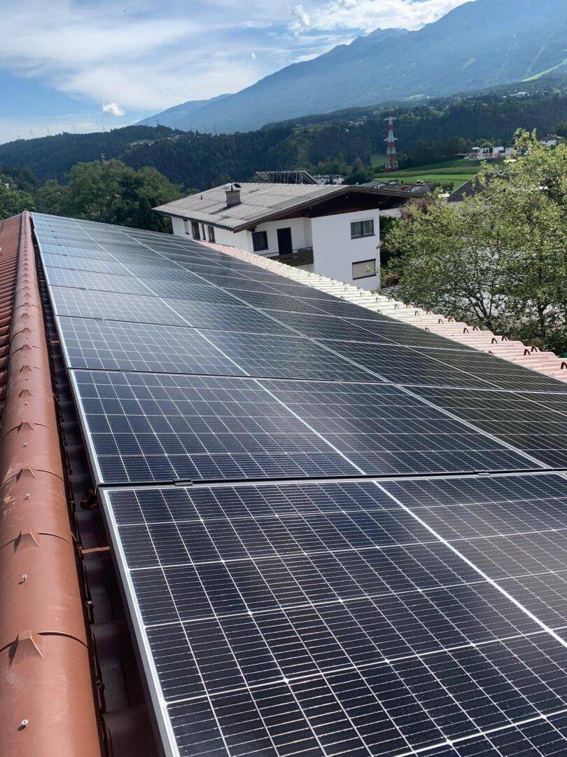 Dach mit installierten Photovoltaik-Modulen zur nachhaltigen Energiegewinnung und Bergblick.