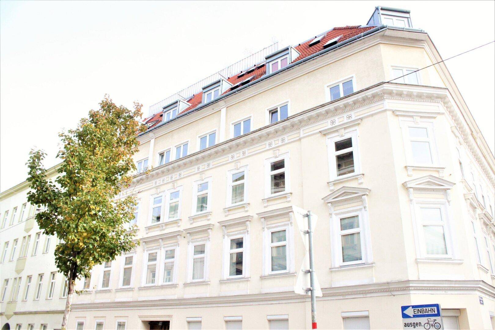 Historisches Eckgebäude mit klassischer Fassade, vielen Fenstern und Mansarddach.