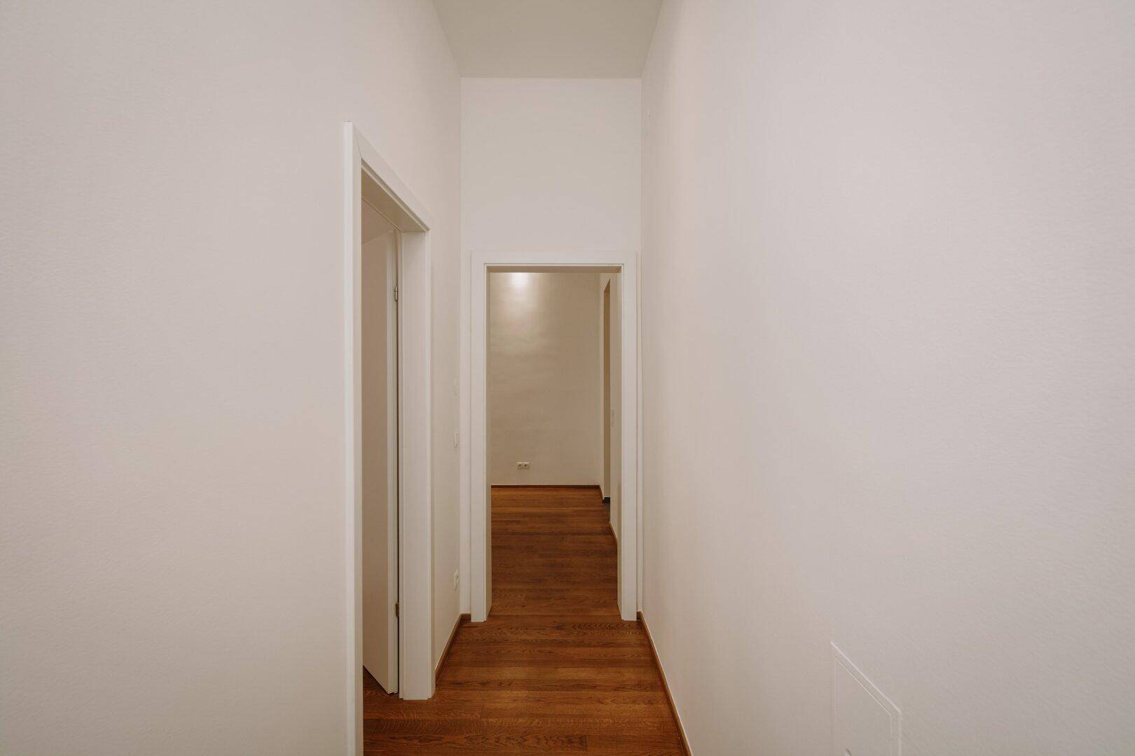 Langer, heller Flur mit Holzboden, der zu weiteren Räumen führt.