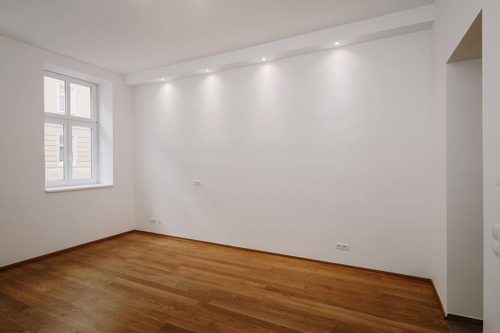 Heller Raum mit Holzboden und Einbaustrahlern, bereit zur individuellen Gestaltung.