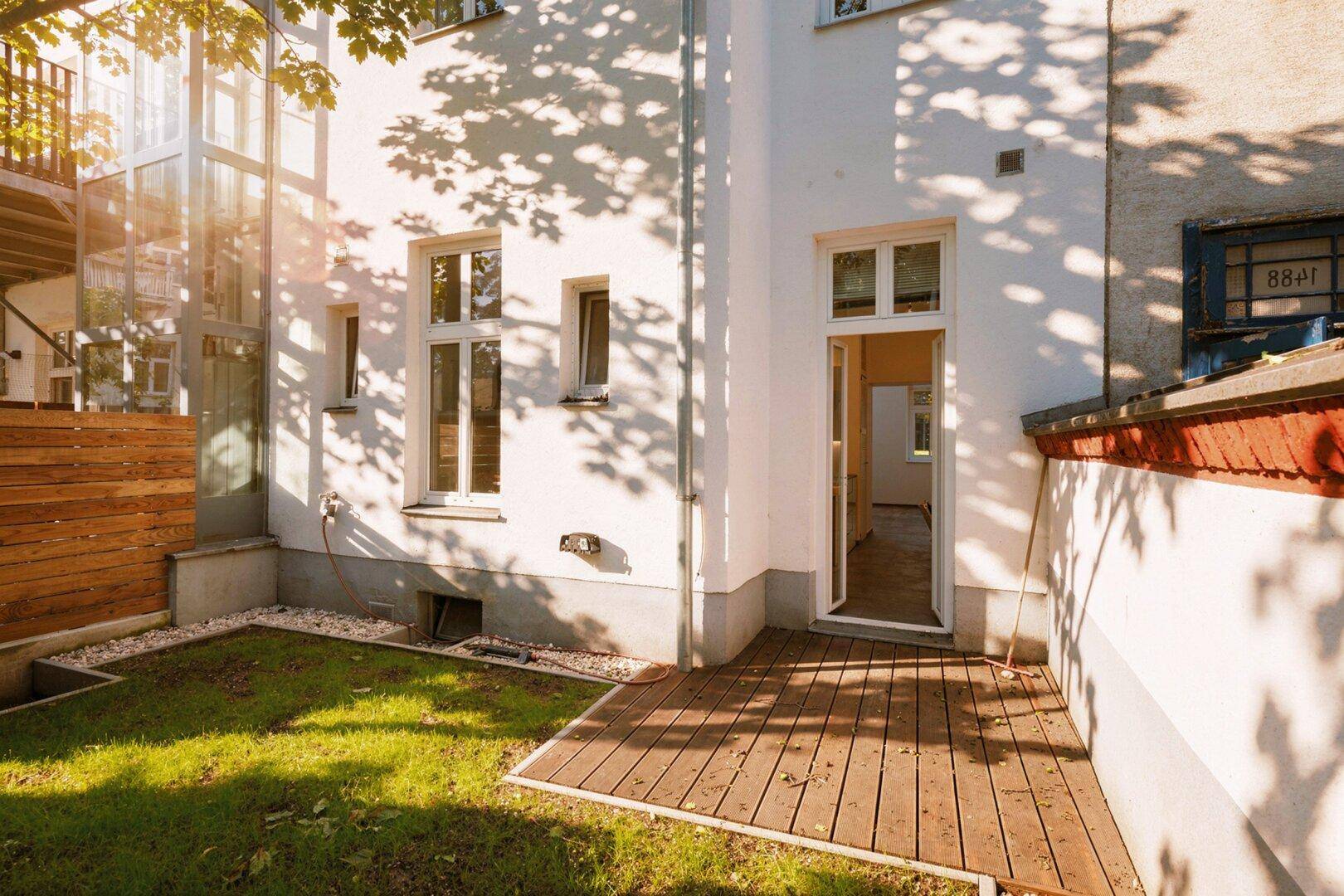 Kleiner Gartenbereich mit Holzterrasse und direktem Zugang zum Innenraum der Wohnung.
