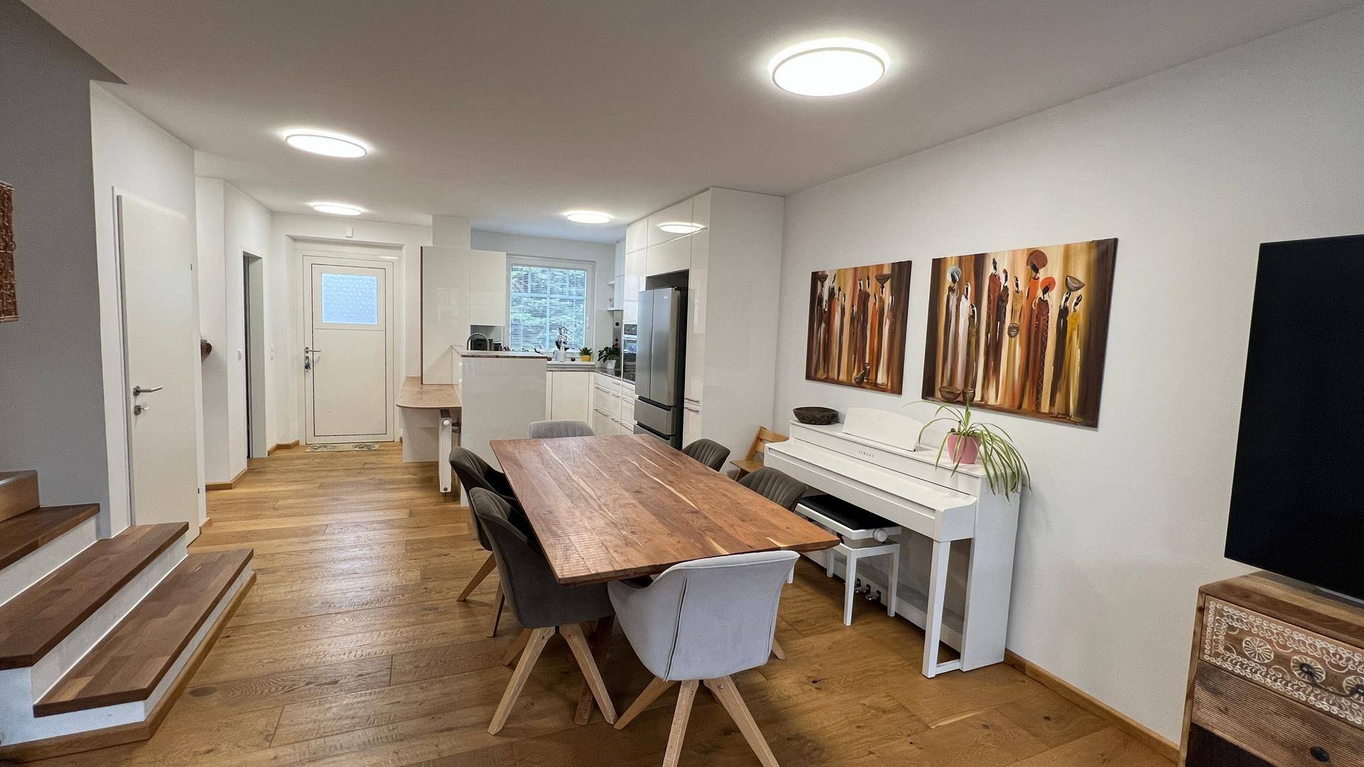 Heller Essbereich mit großem Holztisch, modernen Stühlen und Blick in die offene Küche.