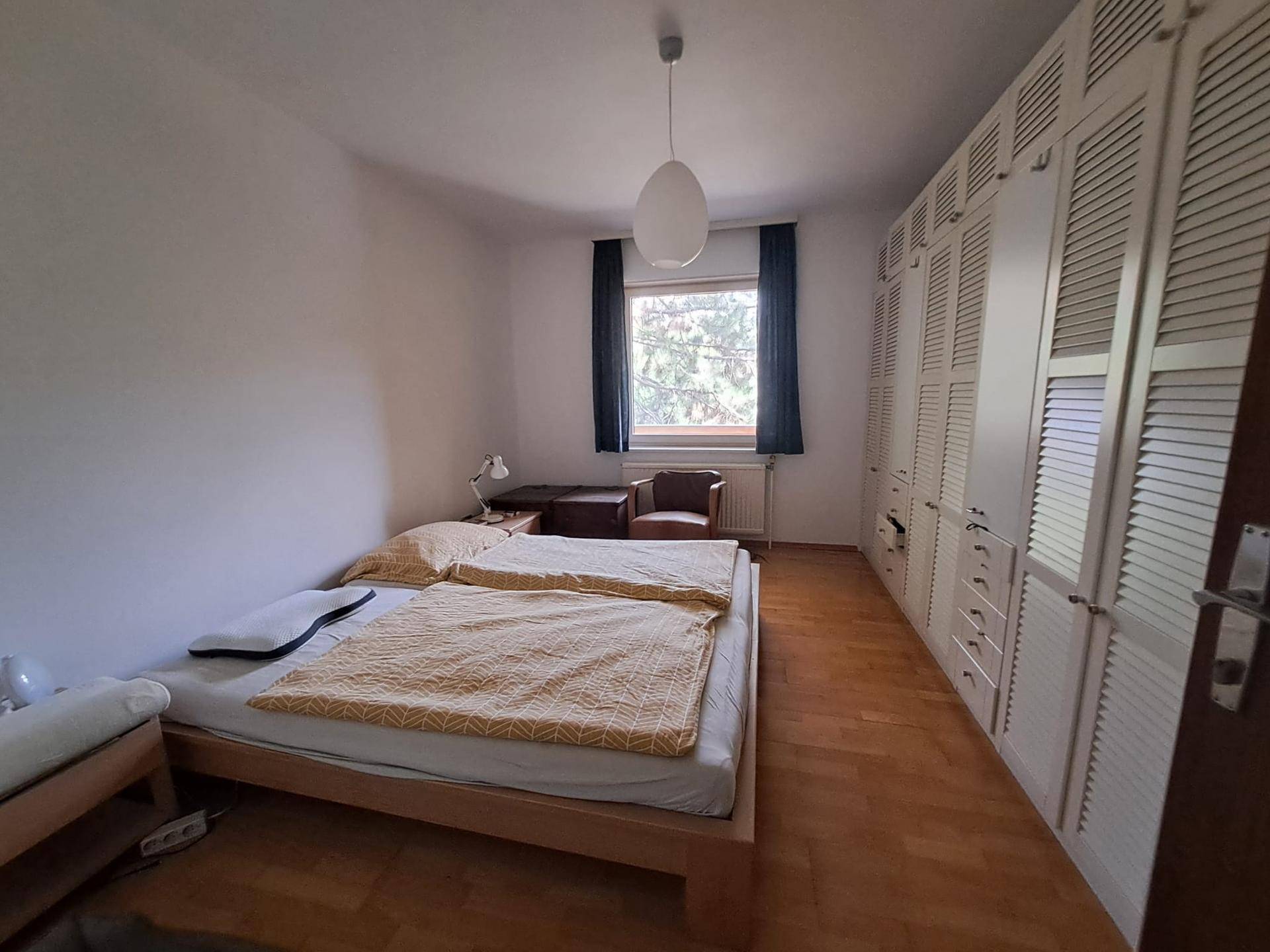 Schlafzimmer mit Doppelbett, großem Fenster und praktischen Einbauschränken entlang der Wand.
