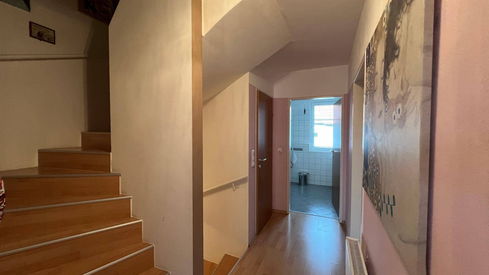 Heller Flur mit Holztreppe und Zugang zu den oberen Etagen, gut beleuchtet.