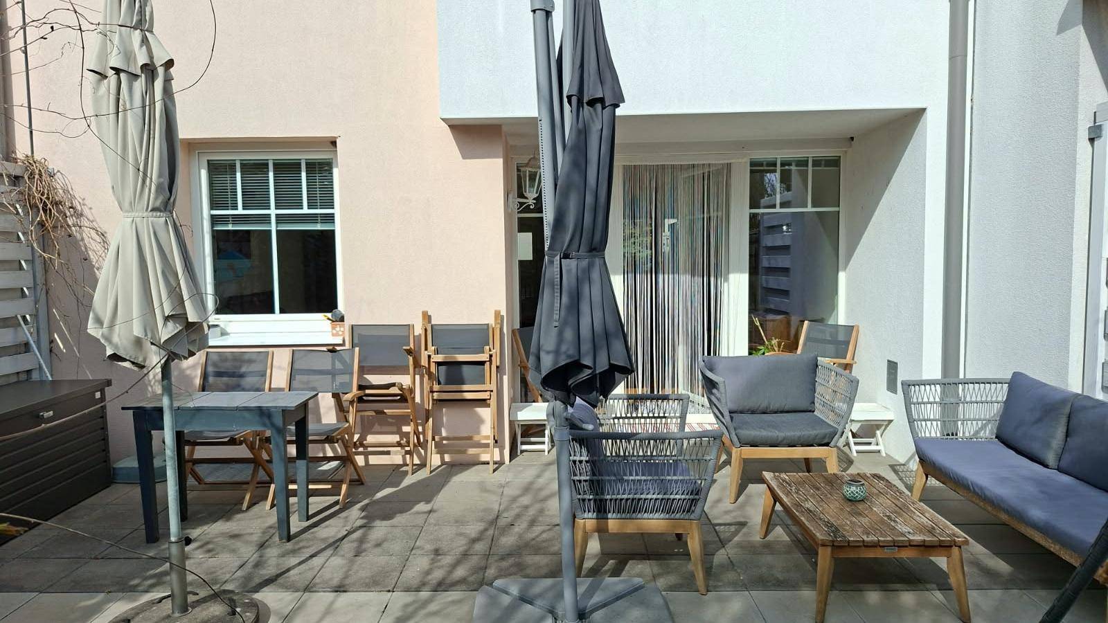 Sonnige Terrasse mit verschiedenen Sitzbereichen und Sonnenschirmen, ideal für Mahlzeiten im Freien.