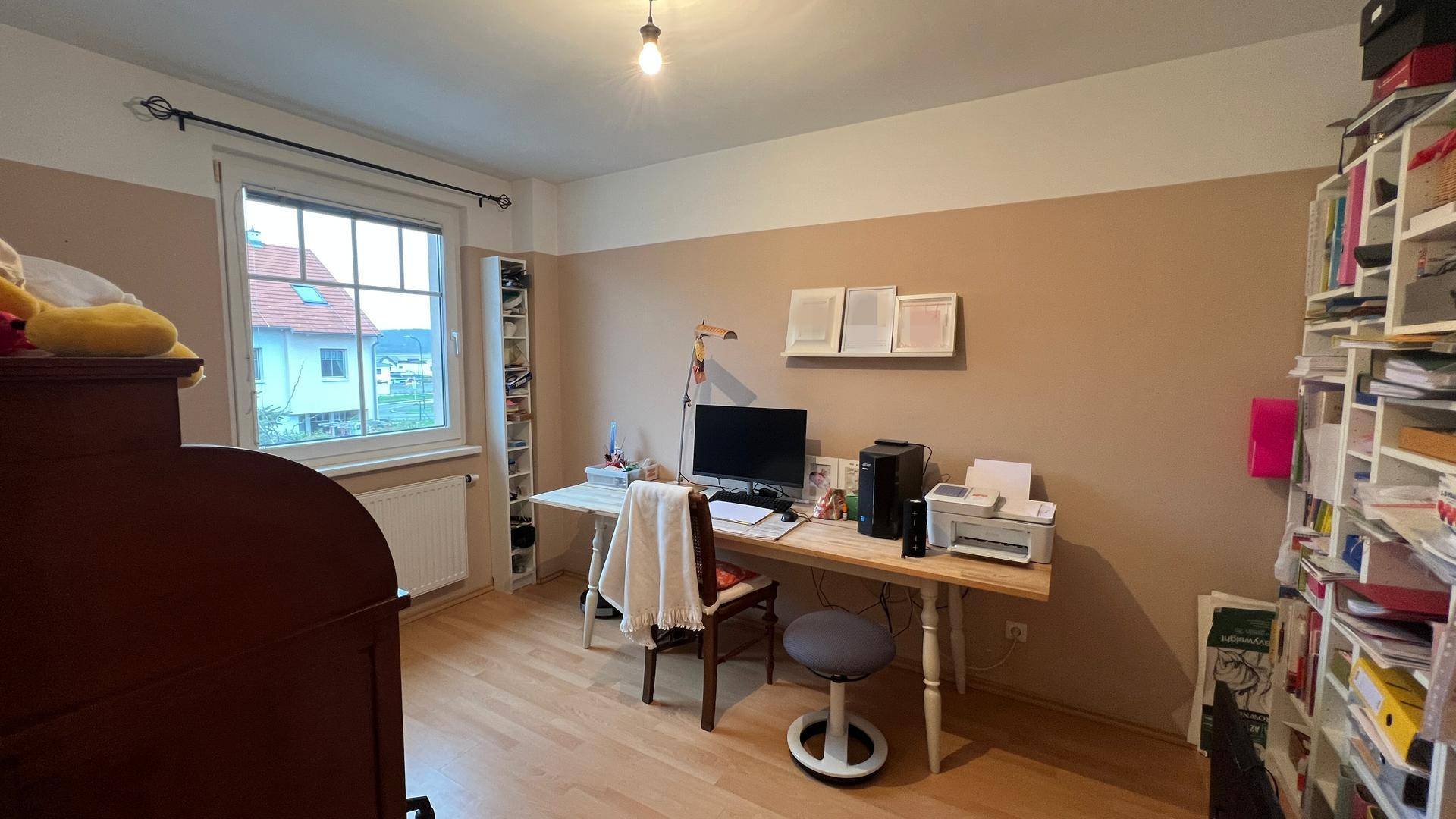 Helles Arbeitszimmer mit Schreibtisch, Bücherregal und Holzboden, ideal für Home-Office.
