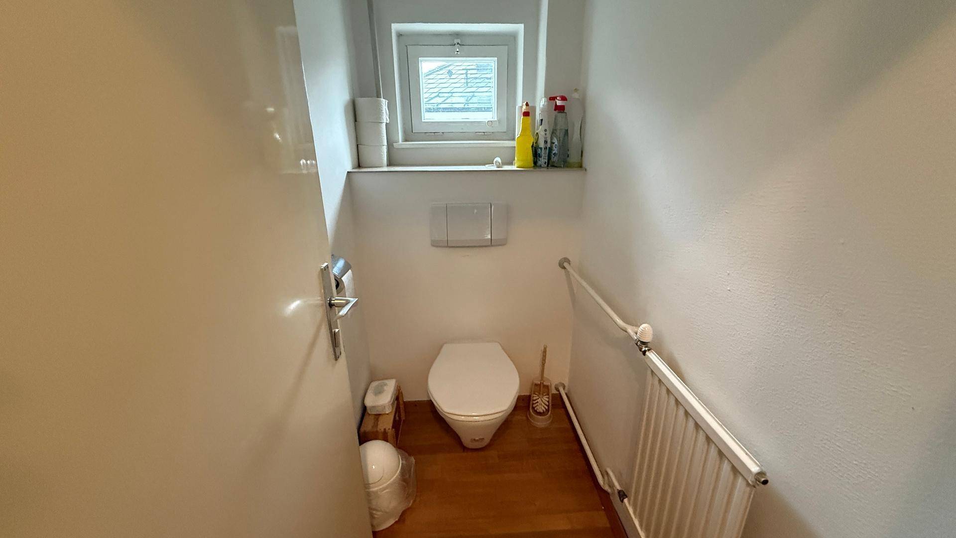 Kleines Gäste-WC mit Fenster, wandhängender Toilette und Heizkörper.