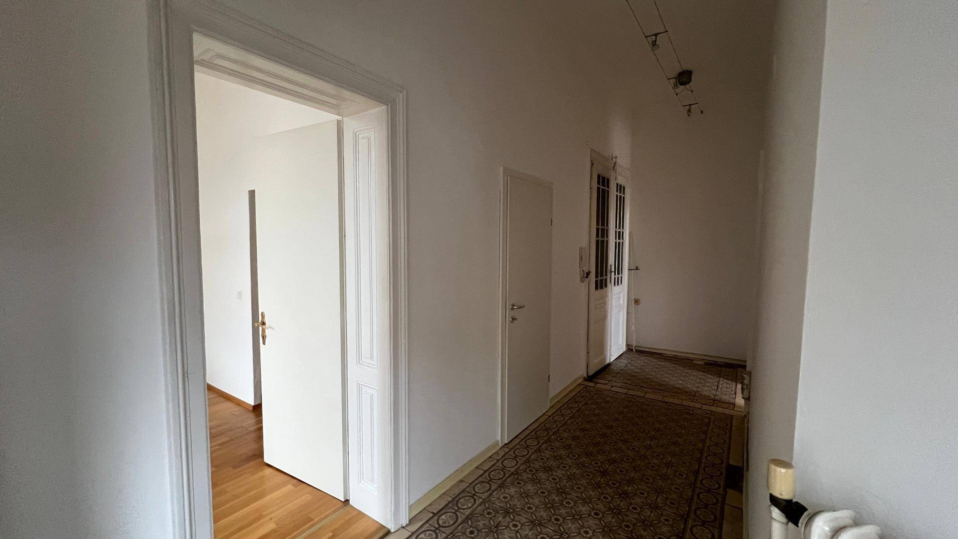 Geräumiger Flur mit gemustertem Teppichläufer, hohen Türen und Zugang zu weiteren Zimmern.