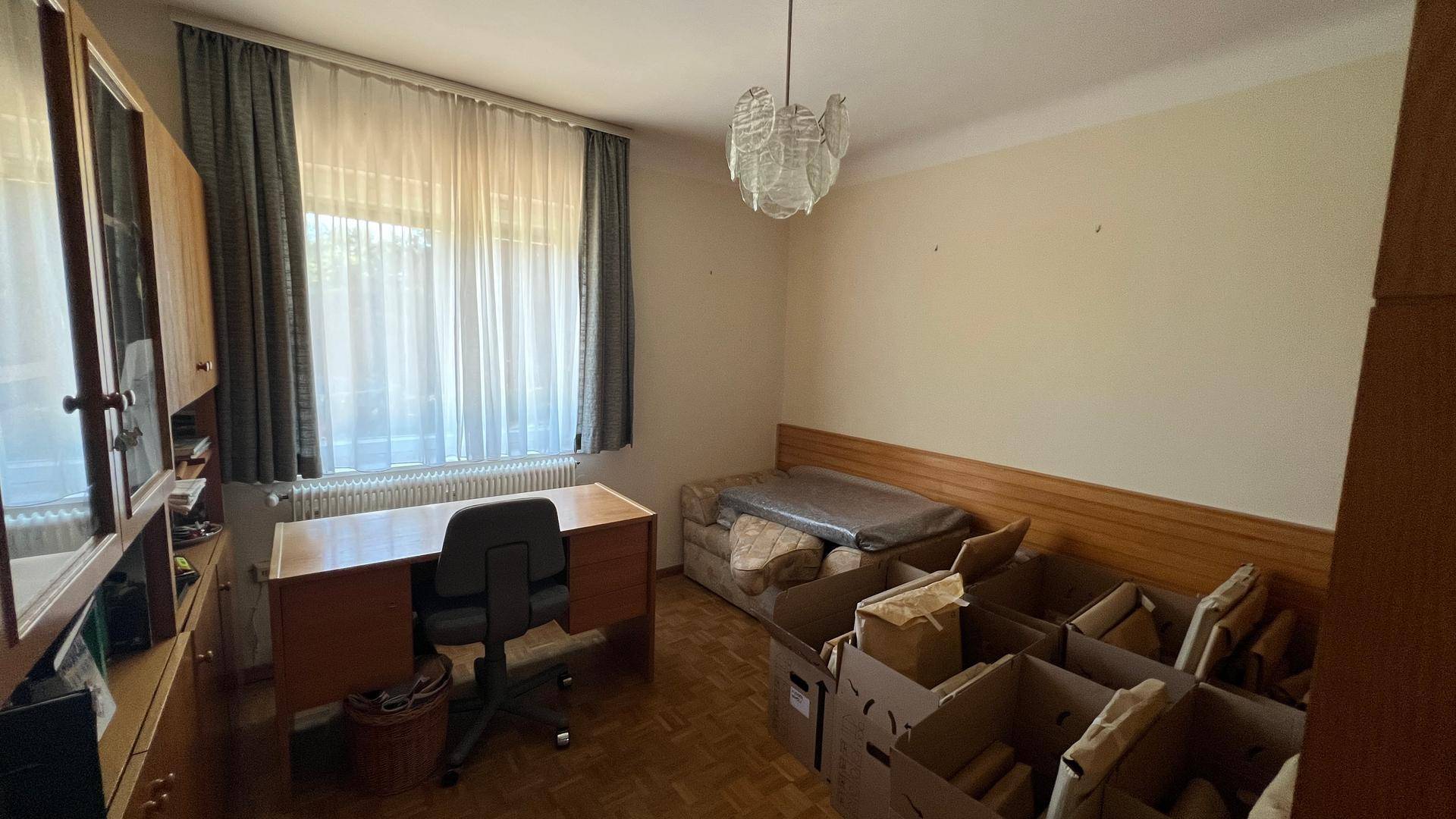 Arbeitszimmer mit Schreibtisch, Bücherregal und Parkettboden, bereit zur Renovierung.