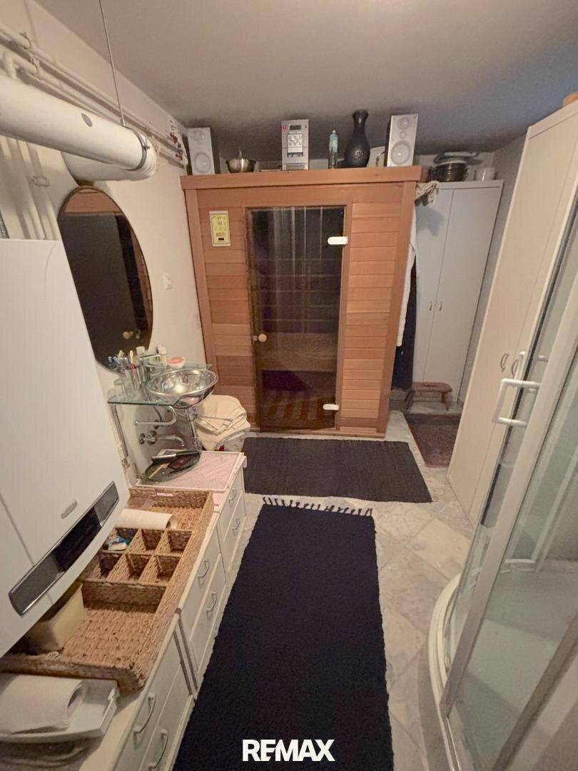 Funktionales Badezimmer mit integrierter Holzsauna, Dusche und Waschtischbereich für Entspannung.