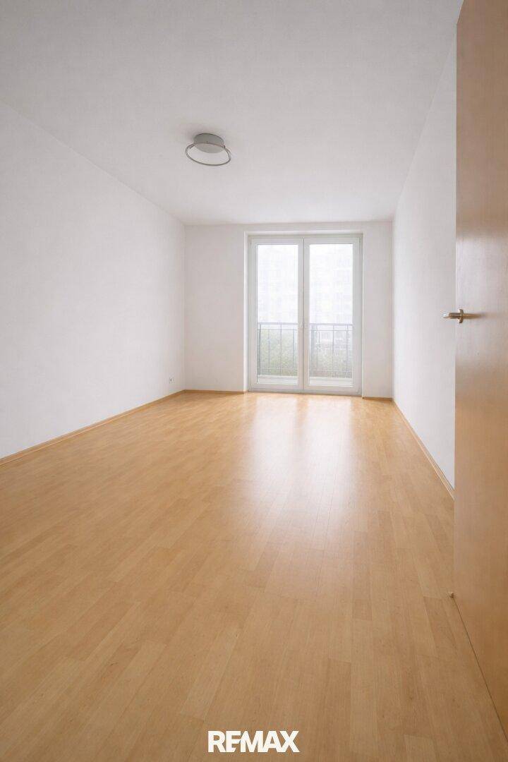 Helles Zimmer mit Laminatboden und französischem Balkon, ideal als Schlafzimmer.
